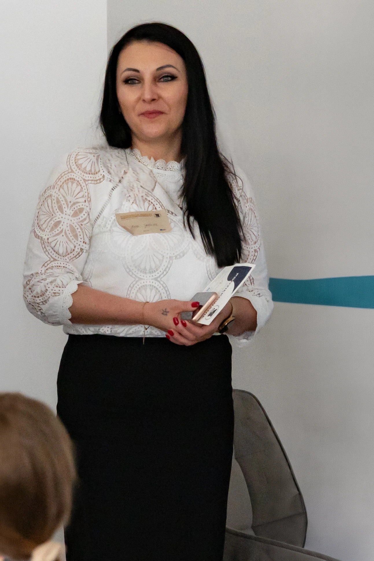 Anna Gancarek - w białej bluzce i czarnej spódnicy, spogląda na uczestników